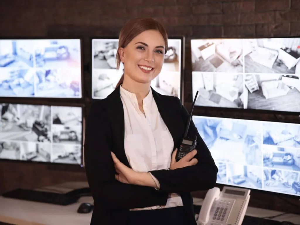 Mujer trabajadora de empresas de seguridad con pantallas de control de cctv de fondo