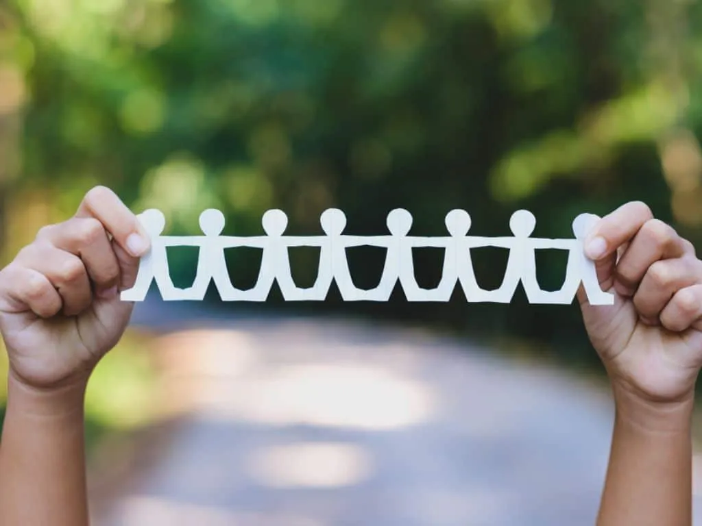 Muestra manual de cadena humana de papel al aire libre en el bosque para así simbolizar las acciones de responsabilidad social empresarial que benefician a un gran grupo de personas