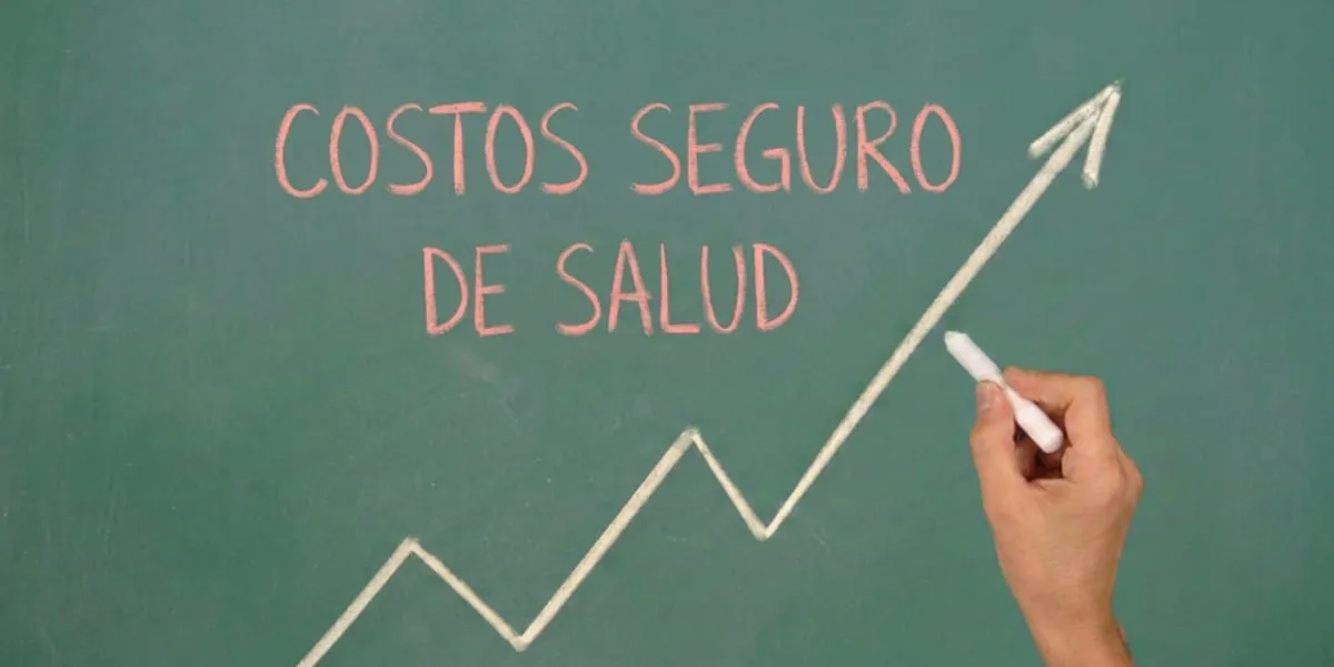 Mano con tiza dibuja una flecha al alza en una pizarra que dice costos de seguro de salud.