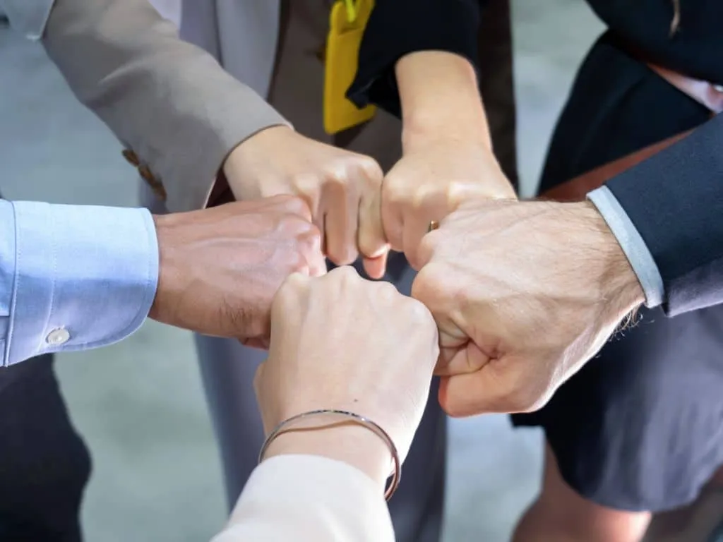 Equipo de trabajo chocando puños en señal de compañerismo