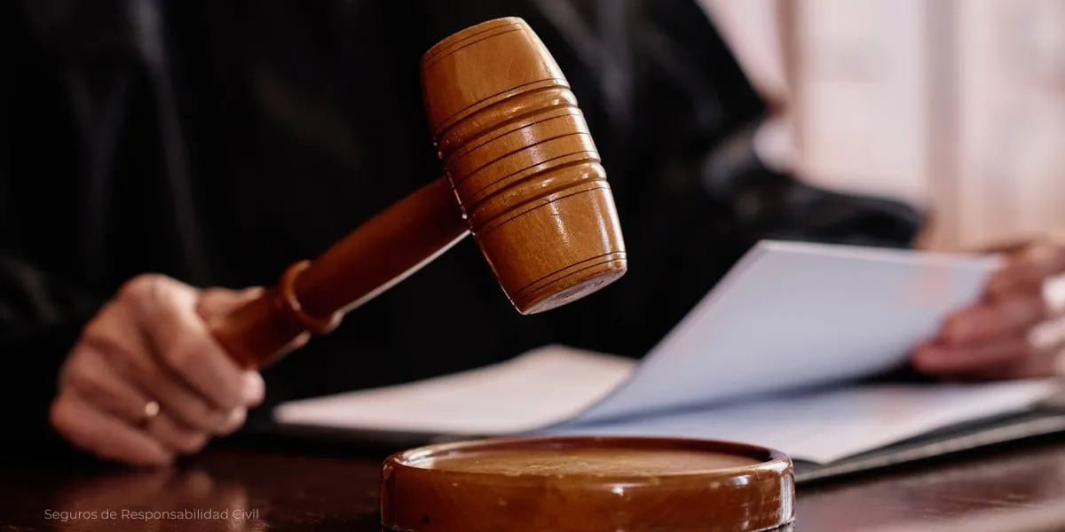 Mano con un mazo de madera sobre documentos, en un escritorio.