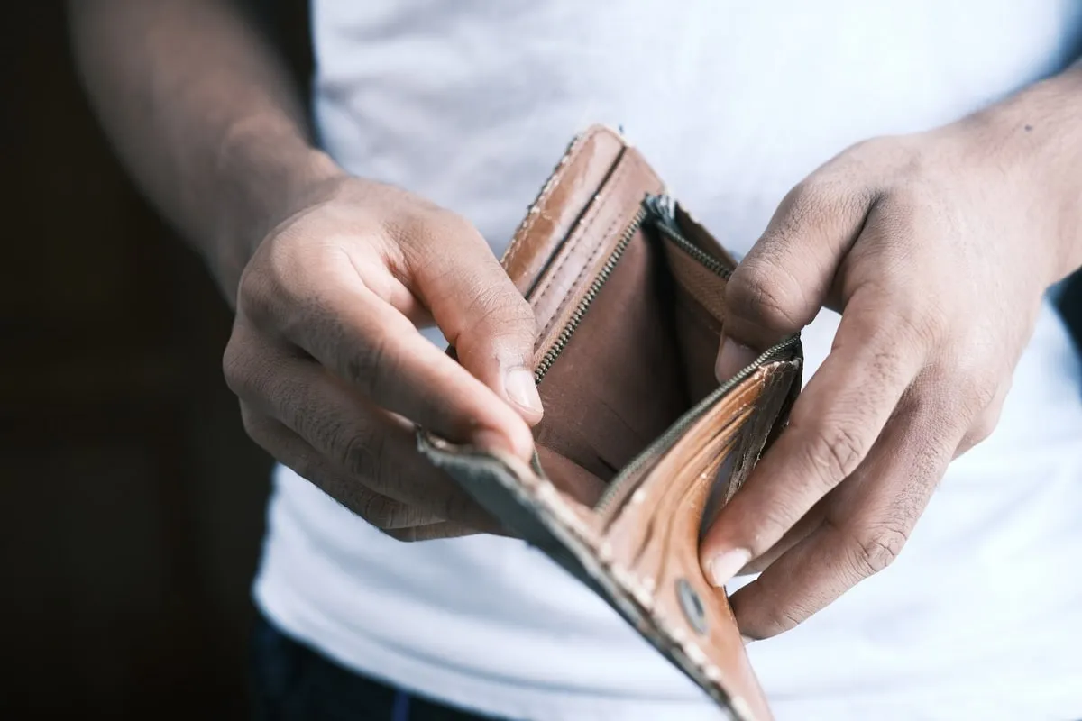Persona abre una billetera de cuero vacía.