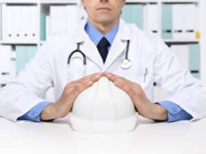 Imagen alegórica al seguro de salud para empleados donde se muestra a un doctor en un consultorio médico agarrando un casco de trabajador simbolizando protección