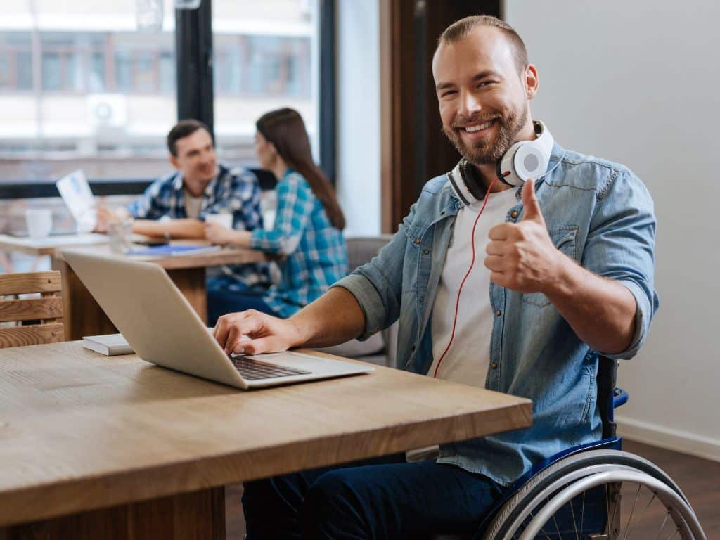 Hombre en silla de ruedas frente a una laptop trabajando en un espacio de trabajo reflejando la inclusión laboral en las empresas