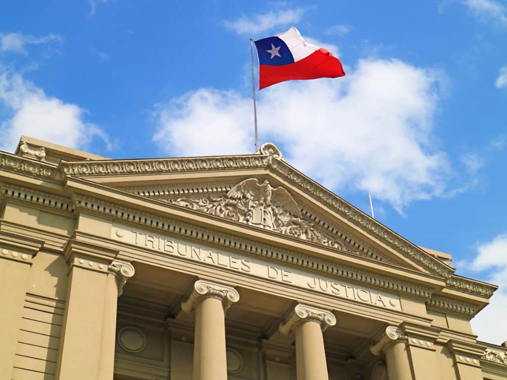 Fachada del edificio de tribunales de justicia chileno con la bandera nacional ondeando encima, imagen en referencia a la intervención de la justicia en el tema de crisis de las Isapres