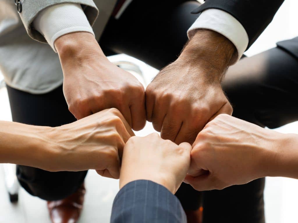 Cinco manos cerradas en puño se juntan como símbolo de unión y esfuerzo en recursos humanos