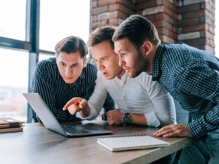 Tres hombres jóvenes miran con sorpresa una pantalla de computador al conocer los mitos de las aseguradoras en Chile.